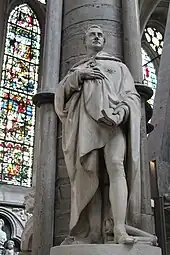 Die Statue Castlereaghs im nördlichen Querschiff der Westminster Abbey, die vor einer Säule steht, hinten links die Fenster der Westminster Abbey mit farbigen Motiven