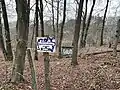WC Haus vom Waldweg und vor dem Zaun aus gesehen