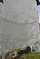 Die auf Fels stehende Ostwand des Chores. Oberhalb der Kette sind die Konturen eines Rundbogenfensters erkennbar