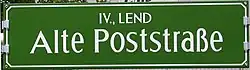 Grazer Straßenschild im Bezirk Lend, Stahlblech, gekantet, gelocht, emailliert, geöst; mittels Aluprofilklemmen mit Kunststoffkappen gehaltert