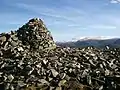 Der Gipfelcairn des Meall a’ Bhuachaille, im Hintergrund der 1090 Meter hohe Bynack More