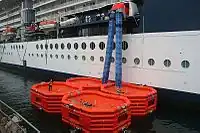Blaue Rettungsschläuche führen von  einem Kreuzfahrtschiff zu aufblasbaren Rettungsinseln