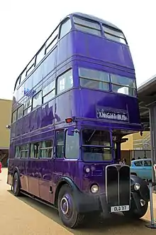 Seitliche Farbfotografie von einem blauen Triple-Decker-Bus mit drei Etagen, auf dessen Anzeigetafel „Knight Bus“ steht.