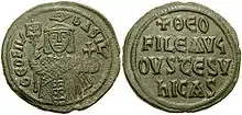 Image of bronze coin, a standing crowned man holding a labarum and a globus cruciger on the obverse, with a Greek-Latin inscription on the reverse