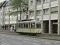 Der historische Credé-Triebwagen (Tw) 113, ein Museumswagen der Braunschweiger Straßenbahn, im Jahr 2009 auf inzwischen an die östliche Straßenseite verlegten Gleisen in Höhe des ehemaligen Standortes des Alten Ministeriums, der inzwischen mit, der Unterbringung von Dienststellen der Stadtverwaltung dienenden, neuem Gebäude Nr. 52 überbaut ist.