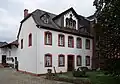 Thebäerstraße 49: ehemalige Kurie des Stifts St. Paulin; fünfachsiger barocker Krüppelwalmdachbau, bezeichnet 1768, Zwerchhaus wohl kurz nach der Mitte des 19. Jahrhunderts.