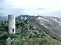 Die trigonometrische Säule auf dem Gipfel des An Socach, im Hintergrund der An Riabhachan