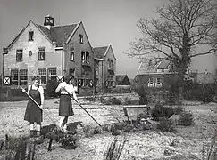 Schülerinnen bei der Arbeit, im Hintergrund das Schulgebäude, April 1946