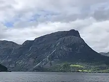 Foto eines Sees, auf dessen gegenüberliegender Uferseite ein Berg liegt