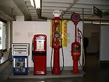 Historische Zapfsäulen im Deutschen Museum (rechts eine „Eiserne Jungfrau“)