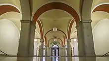 Eingangshalle mit Mitteltreppe, Säulen und Kreuzgewölbe.