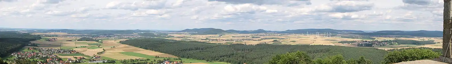 Nordostblick von der Weidelsburg: Links vorne der Ippinghäuser Grund mit Ippinghausen und dem tiefer gelegenen Weiler Leckringhausen, schräg rechts dahinter Wolfhagen und der Ofenberg (372,5 m; 6,8 km entfernt) rechts der Stadt und am Westrand des Altenhasunger Grabens; weiter rechts der Isthaberg (523,1 m; 7,1 km) und schließlich die Isthaebene mit Bründersen vor Istha vor Oelshausen (Mitte) und Altenstädt vor Balhorn (rechts), die zum Ippinghäuser Grund hin vom bewaldeten  Rauenstein gerahmt wird. Hintere Reihe: Links hinter den Windkraftanlagen Stromberg (362,2 m; 14,0 km) und Heidelbeerenberg (398 m; 13,3 km), rechts dahinter der Desenberg (343,6 m; 25,6 km); links des Ofenbergs der Warteberg (419 m; 9,8 km), zwischen beiden der Escheberg (448,9 m; 16,0 km); in der Bildmitte, hinter dem Isthaberg, der Große Bärenberg (600,7 m; 12,3 km) mit Funk- und Aussichtsturm, weiter rechts der Dörnberg (578,7 m; 16,7 km); hinter den Windkraftanlagen schließlich der Hohe Habichtswald (614,8 m; 15,1 km) und rechts der Schwengeberg (556,7 m; 14,0 km).Für eine detailliertere Beschreibung siehe Weidelsberg#Aussicht!