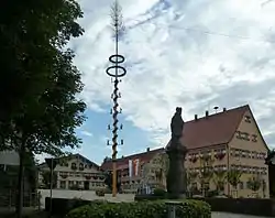 Kirchplatz samt Rathaus und benachbarten Gebäuden. Maibaum in der Mitte des Platzes