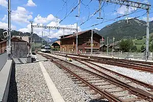 Die abgestellte MOB-Lokomotive, die den Zug nach Montreux schieben wird, wartet am Nordkopf des Bahnhofs auf dem für beide Umspuranlagen benutzten, meterspurigen Kehrgleis.Rechts unten u. rechts: Ausfädelstellen aus Vierschienengleisen.