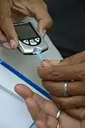 Aufbringen eines Bluttropfens aus der Fingerbeere auf den Blutzucker­teststreifen (2015)